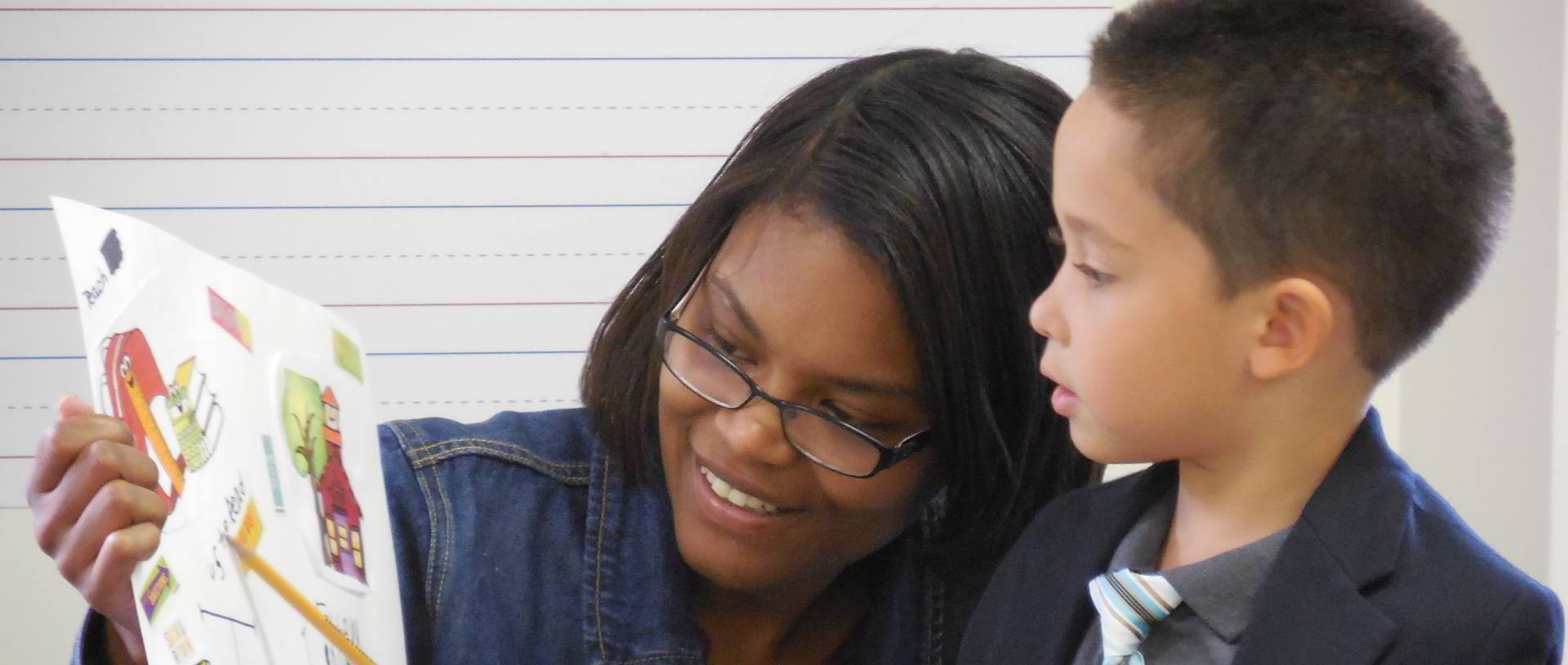 A woman reads with a boy.