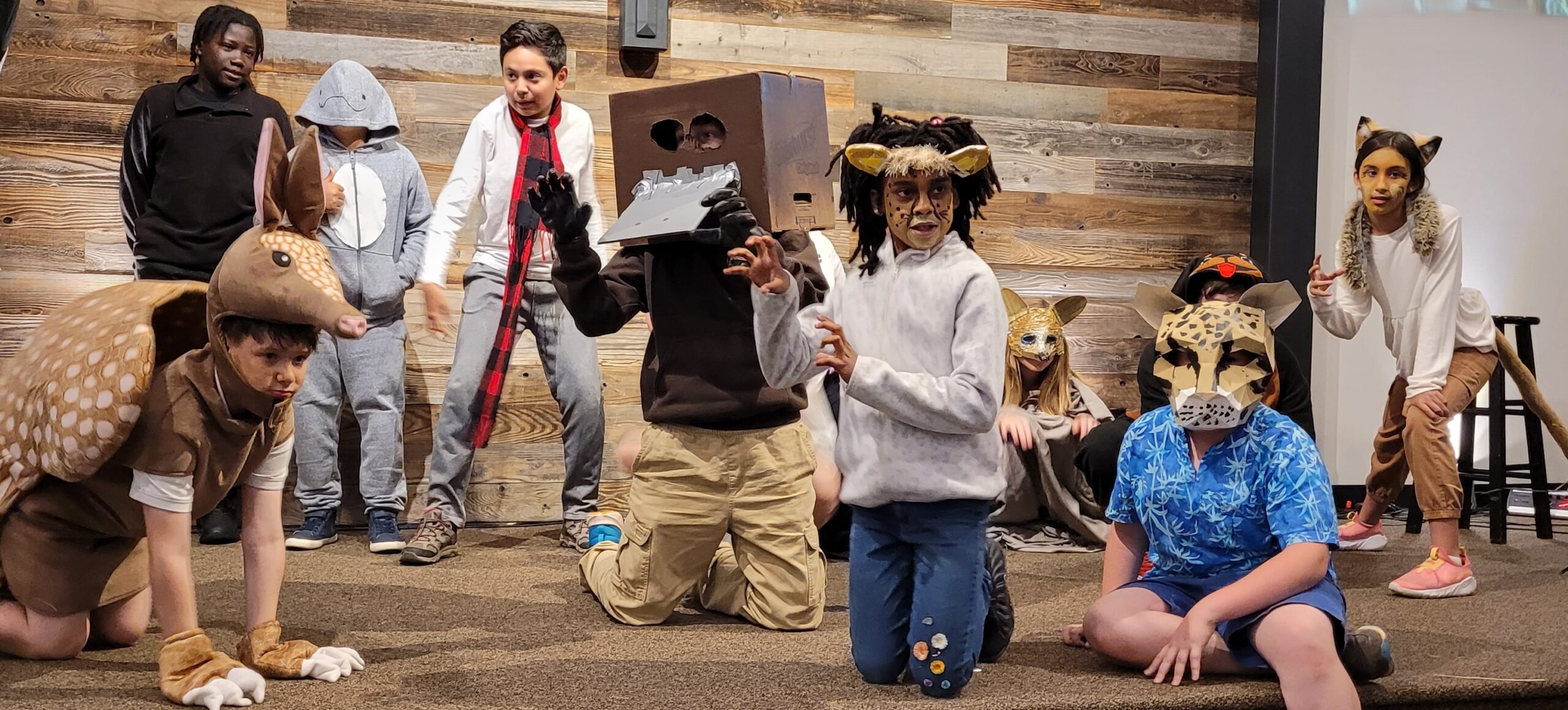 Students pose on a stage as animals