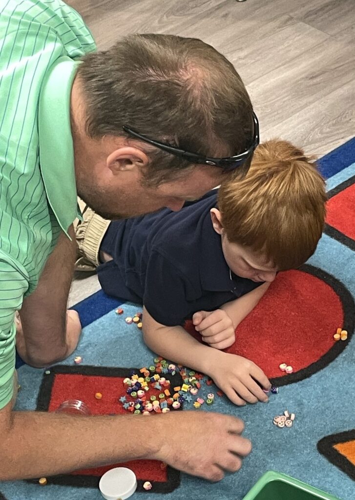 Man helps a boy sort colored pieces