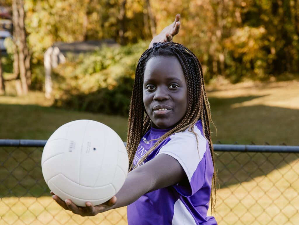 A girl wearing a Community Christian Academy athletic shirt prepares to serve a volleyball