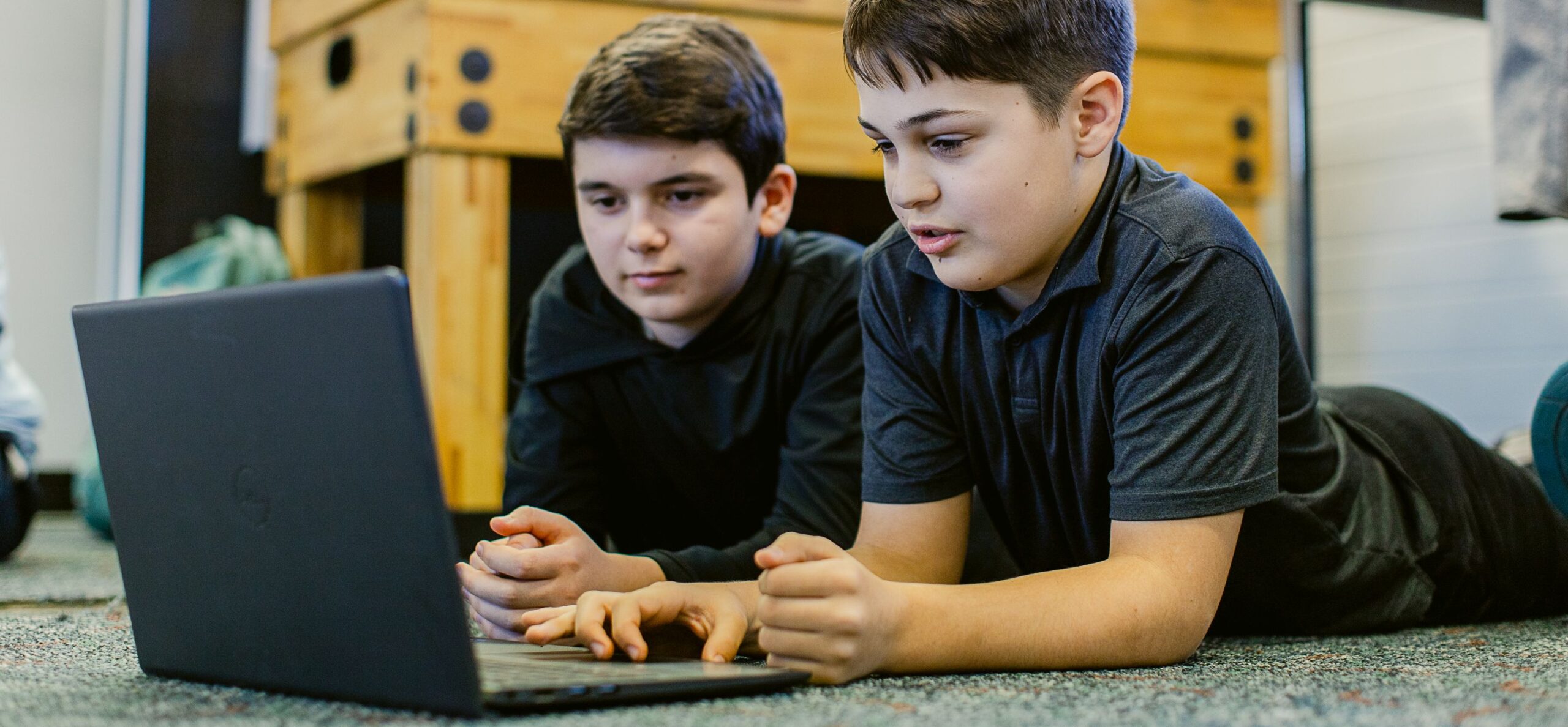 Two boys are looking at a laptop