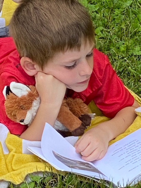 Boy with a stuffed animal reads a book