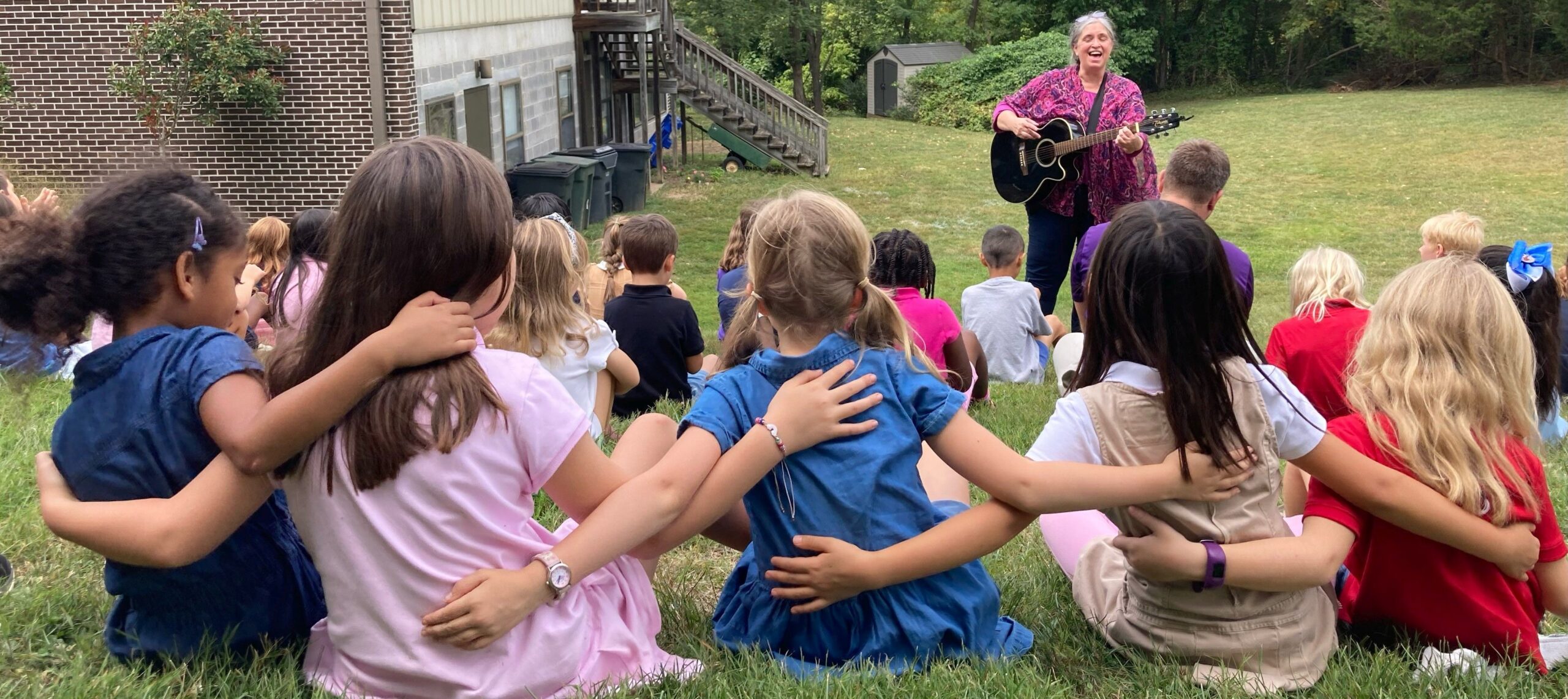 Children listening to a person playing guitar.