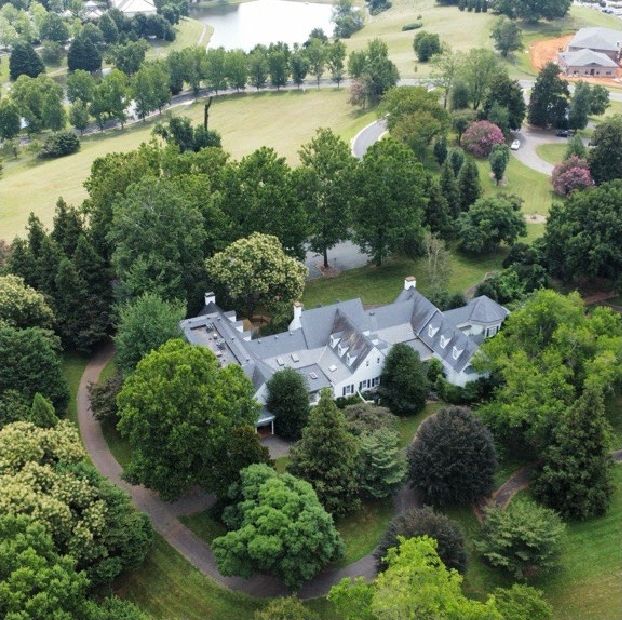 Aerial view of Worrell Drive property shows shows a mansion surrounded by lush green trees 