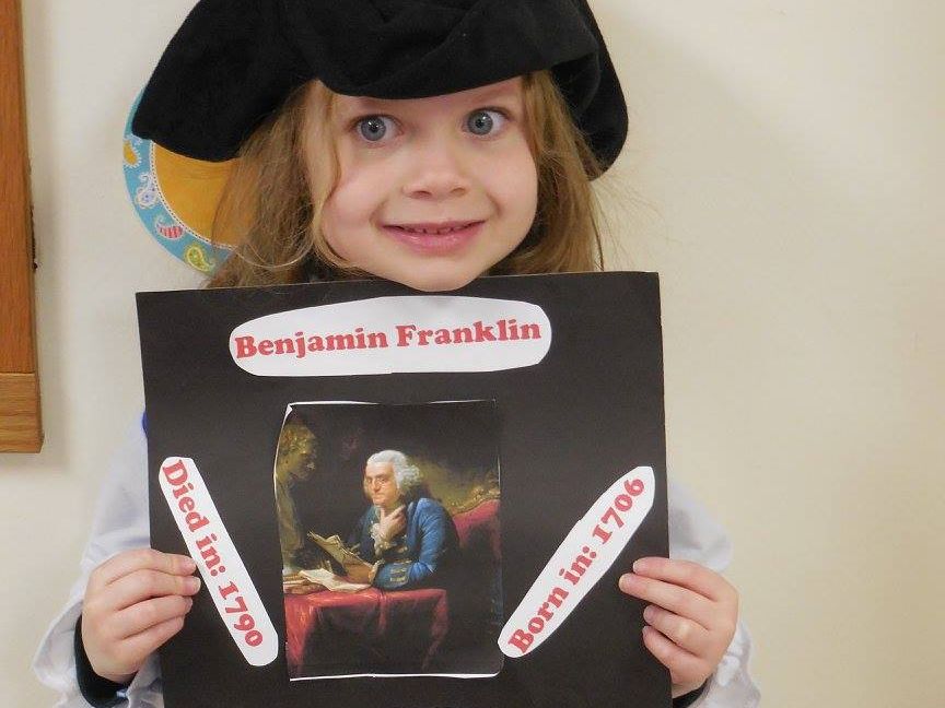 Girl holds her Benjamin Franklin poster project