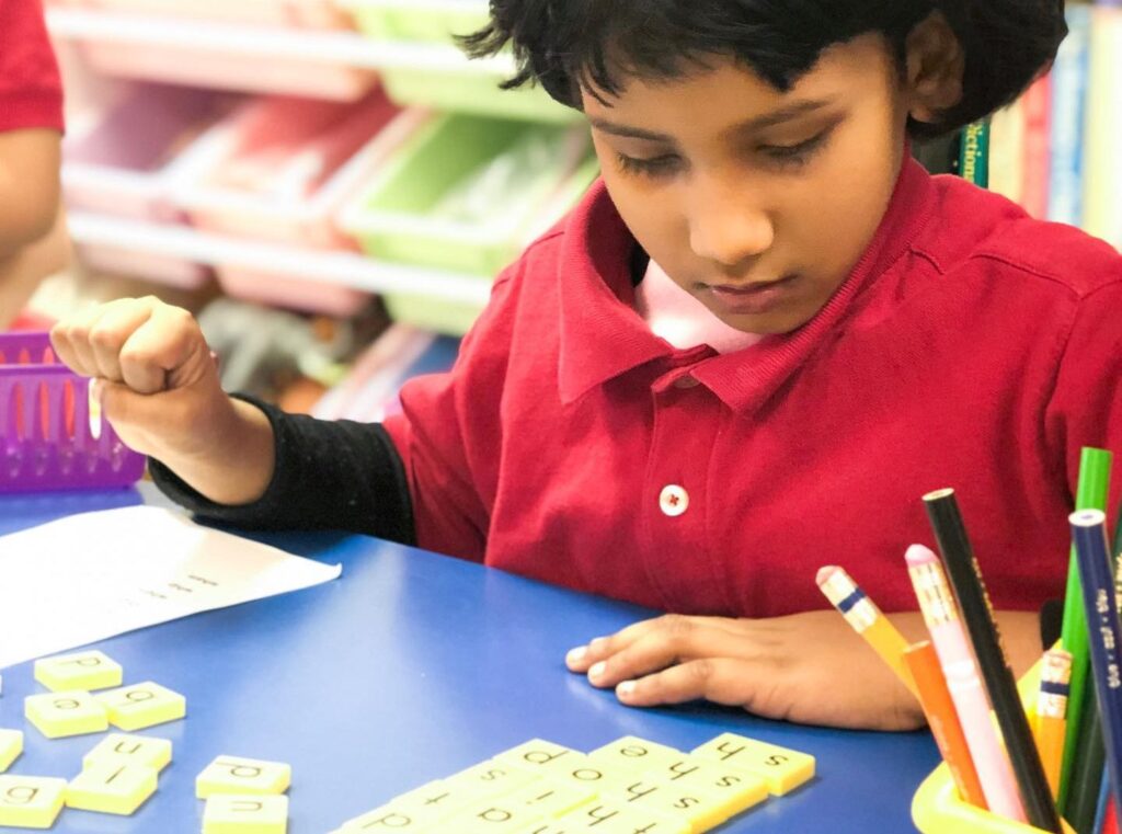 Girl arranges letter tiles on a table