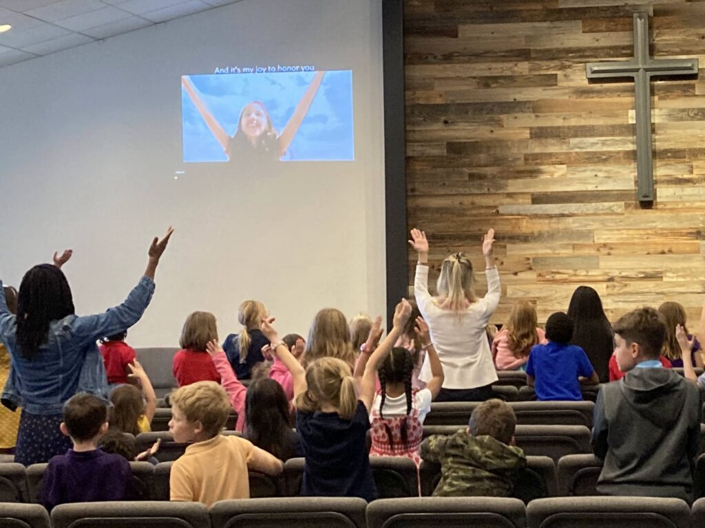 Students stand with arms raised in a chapel